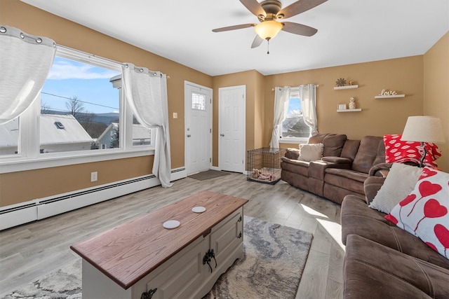 living room featuring ceiling fan, baseboard heating, and light hardwood / wood-style flooring