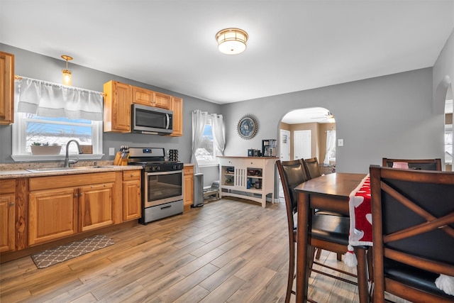 kitchen featuring sink, light wood-type flooring, appliances with stainless steel finishes, pendant lighting, and ceiling fan