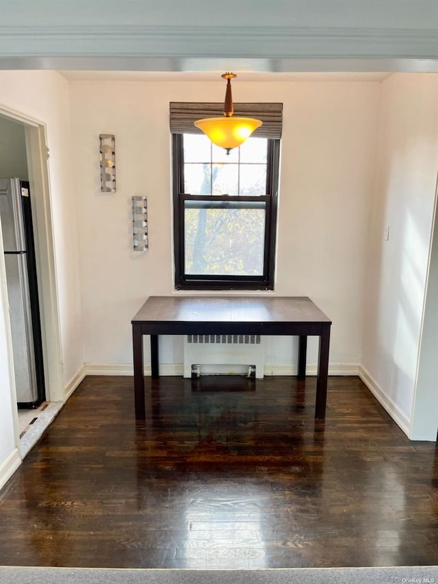 unfurnished dining area with ornamental molding, radiator heating unit, and dark hardwood / wood-style flooring