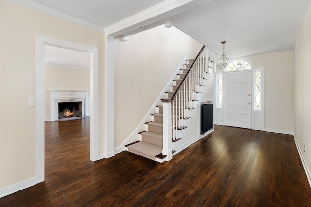 foyer with ornamental molding, dark hardwood / wood-style floors, and a notable chandelier