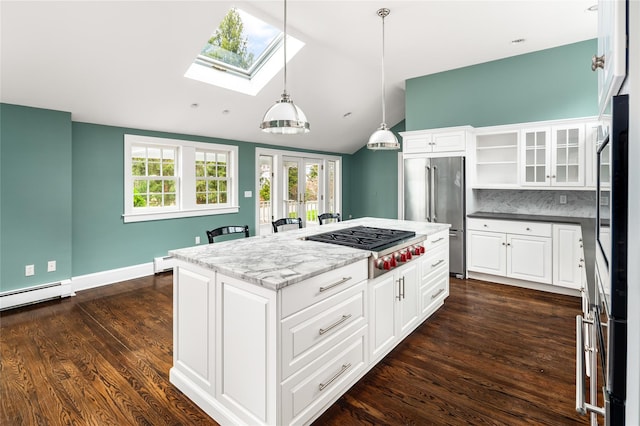 kitchen featuring white cabinetry, appliances with stainless steel finishes, lofted ceiling with skylight, and decorative light fixtures