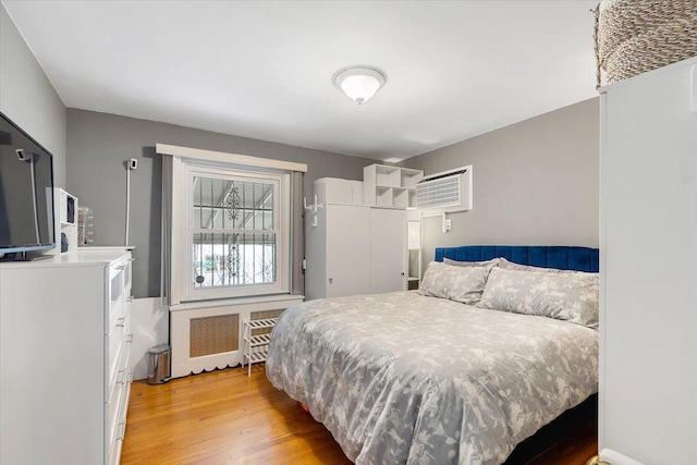 bedroom featuring light hardwood / wood-style floors and a wall mounted AC