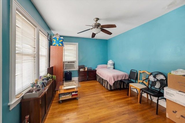 bedroom featuring cooling unit, ceiling fan, and light hardwood / wood-style floors