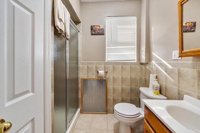 bathroom featuring a shower with door, tile walls, vanity, tile patterned floors, and toilet