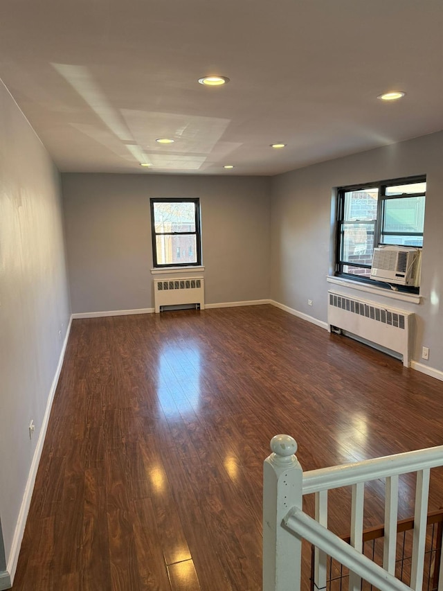 unfurnished living room featuring dark hardwood / wood-style floors, radiator, and a wealth of natural light