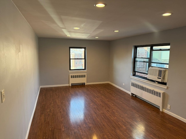 spare room featuring radiator heating unit, a healthy amount of sunlight, and dark hardwood / wood-style floors