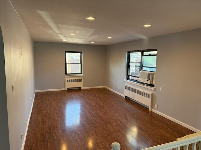 spare room featuring dark hardwood / wood-style floors, radiator, and plenty of natural light