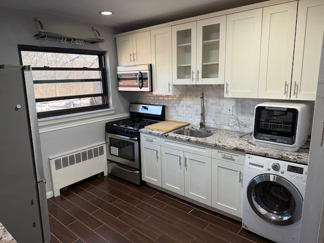 kitchen with white cabinets, radiator heating unit, washer / dryer, stainless steel appliances, and sink