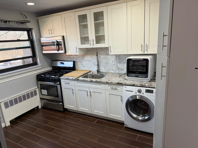 kitchen featuring white cabinets, stainless steel appliances, radiator, and washer / clothes dryer