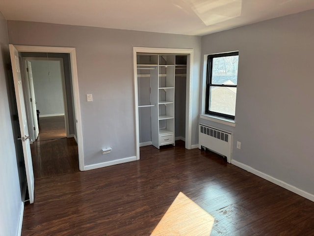 unfurnished bedroom featuring a closet, radiator, and dark hardwood / wood-style floors