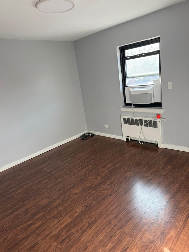 empty room featuring dark wood-type flooring, cooling unit, and radiator