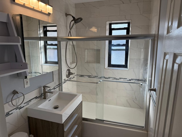 bathroom with tile walls, enclosed tub / shower combo, and vanity