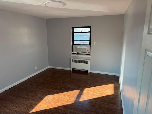 spare room with dark wood-type flooring, cooling unit, and radiator