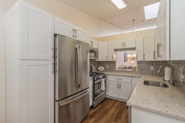 kitchen featuring white cabinets, appliances with stainless steel finishes, sink, backsplash, and light stone counters