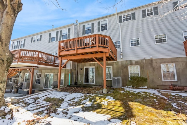 snow covered back of property featuring a wooden deck and central AC unit