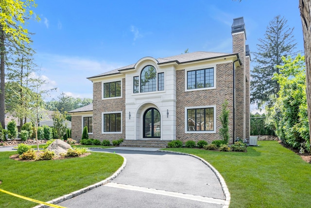 85 Dorchester Dr, Manhasset, NY 11030 - colonial-style house with brick siding, a front lawn, a chimney, central air condition unit, and curved driveway