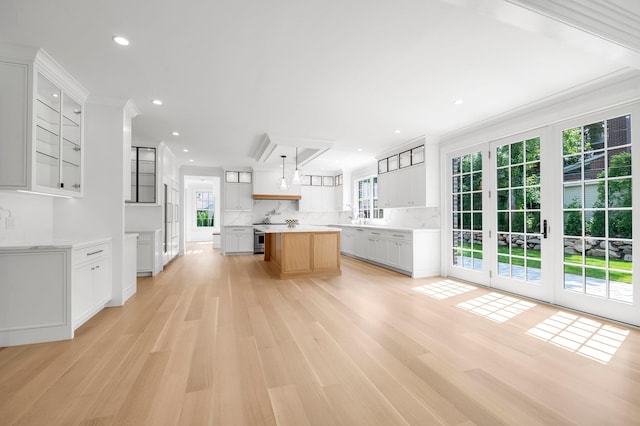 85 Dorchester Dr, Manhasset, NY 11030 - kitchen with light wood-style floors, glass insert cabinets, tasteful backsplash, a kitchen island, and recessed lighting