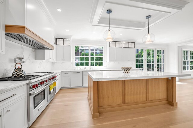 85 Dorchester Dr, Manhasset, NY 11030 - kitchen with range with two ovens, custom exhaust hood, a kitchen island, light wood-type flooring, and crown molding