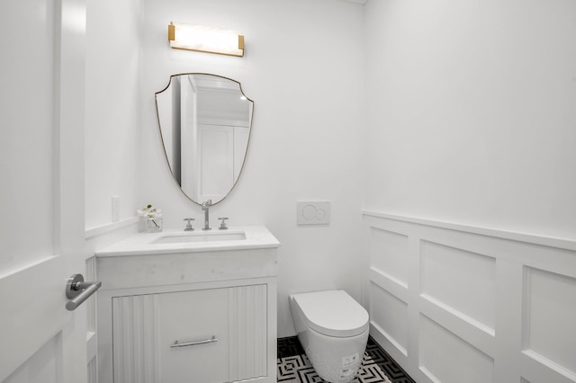 85 Dorchester Dr, Manhasset, NY 11030 - bathroom featuring toilet, vanity, a decorative wall, and a wainscoted wall