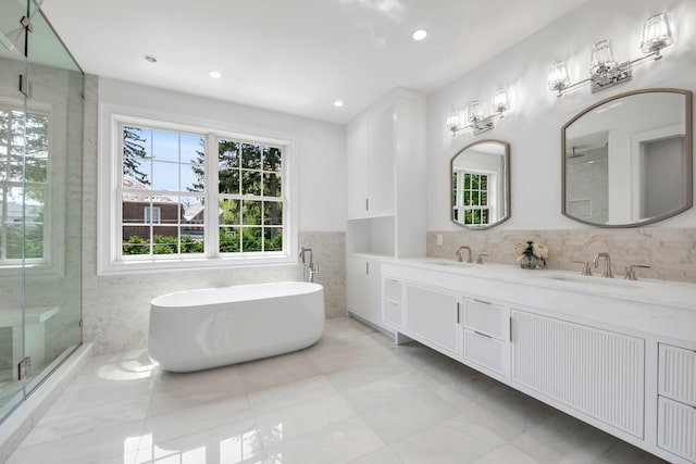 85 Dorchester Dr, Manhasset, NY 11030 - full bathroom with a soaking tub, double vanity, a shower stall, and tile walls