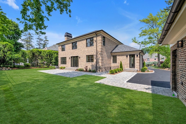 85 Dorchester Dr, Manhasset, NY 11030 - back of house with brick siding, a patio, a chimney, and a lawn