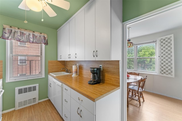 kitchen with sink, dishwasher, ceiling fan, white cabinetry, and radiator heating unit