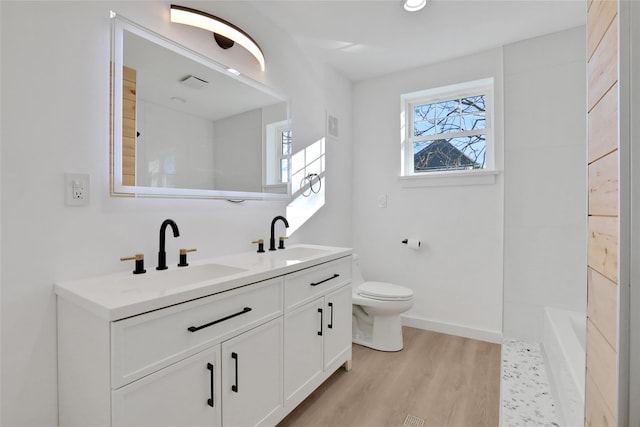 bathroom with wood-type flooring, toilet, a bathtub, and vanity