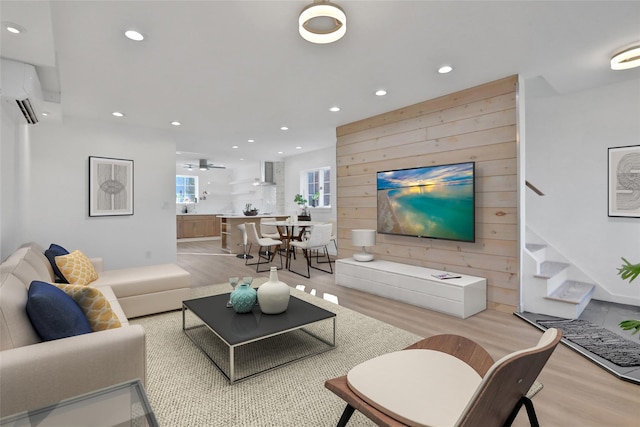 living room featuring light wood-type flooring, a wall mounted AC, and wooden walls