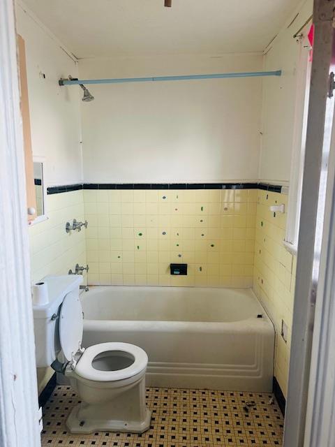 bathroom with toilet, mail boxes, shower / tub combination, and tile walls