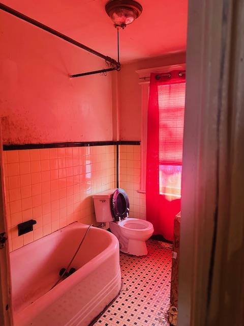 bathroom featuring tile walls and toilet