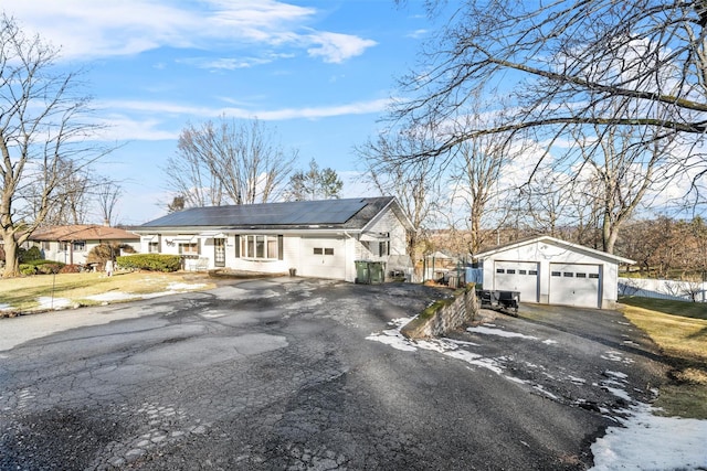 view of front of house featuring a garage, solar panels, and an outdoor structure