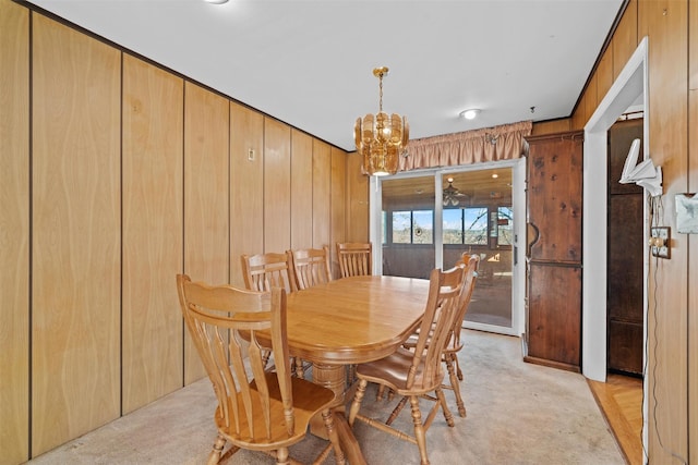 carpeted dining space featuring a chandelier and wooden walls