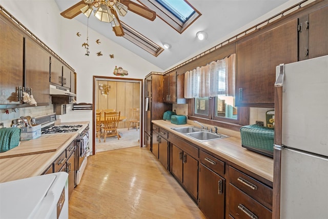 kitchen featuring vaulted ceiling with skylight, sink, range with gas cooktop, ceiling fan, and white refrigerator