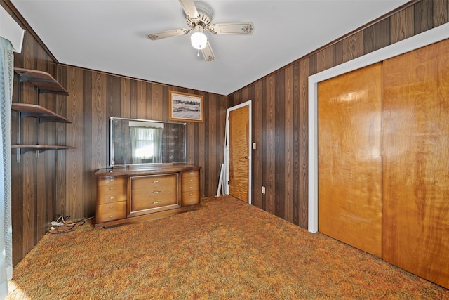 unfurnished office with ceiling fan, wood walls, and carpet