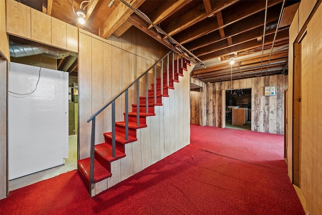 basement with wood walls, carpet flooring, and white refrigerator