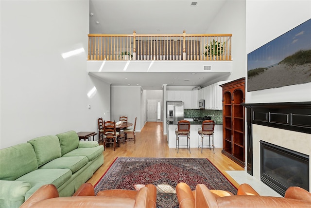 living room featuring a towering ceiling and light wood-type flooring