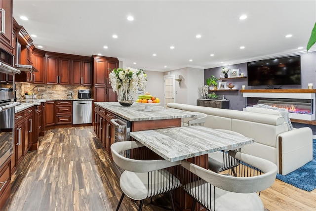 kitchen featuring a kitchen bar, light stone counters, dishwasher, a kitchen island, and decorative backsplash