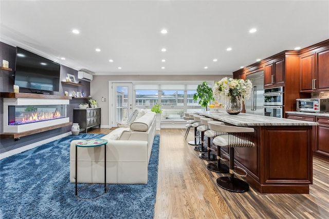 living room featuring hardwood / wood-style flooring, ornamental molding, and a wall mounted AC