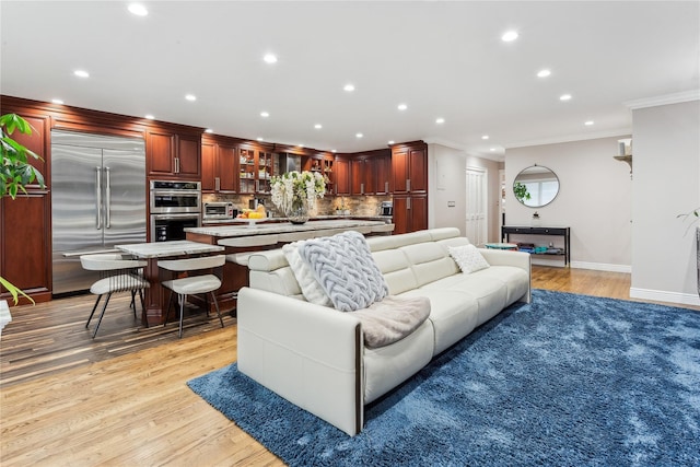 living area with crown molding, recessed lighting, light wood-type flooring, and baseboards