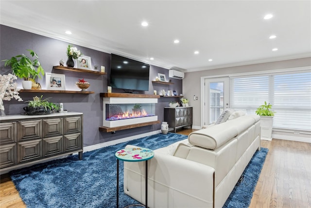 living area featuring an AC wall unit, ornamental molding, recessed lighting, a glass covered fireplace, and light wood-type flooring
