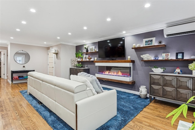 living room with ornamental molding, a wall mounted AC, wood finished floors, recessed lighting, and a glass covered fireplace