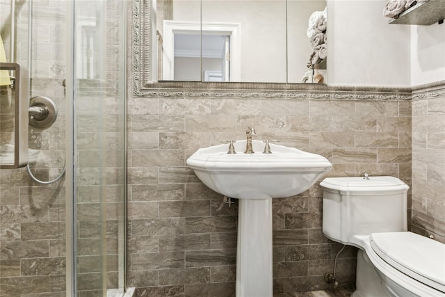 full bathroom featuring tile walls, a stall shower, toilet, and wainscoting