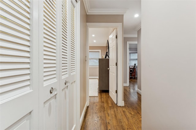 corridor with ornamental molding, wood finished floors, recessed lighting, and baseboards