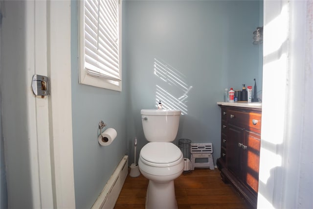 bathroom featuring vanity, toilet, a baseboard heating unit, and wood-type flooring