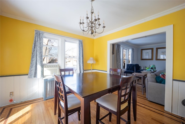 dining area featuring light hardwood / wood-style floors, ornamental molding, and a notable chandelier