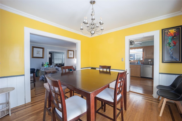 dining room featuring light hardwood / wood-style floors, sink, ornamental molding, and a notable chandelier