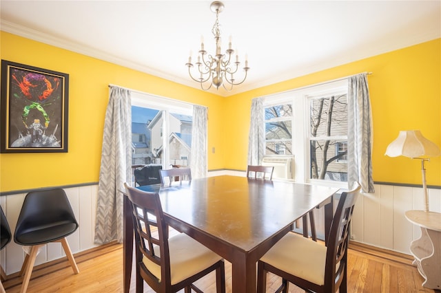 dining room with light hardwood / wood-style flooring, an inviting chandelier, and crown molding