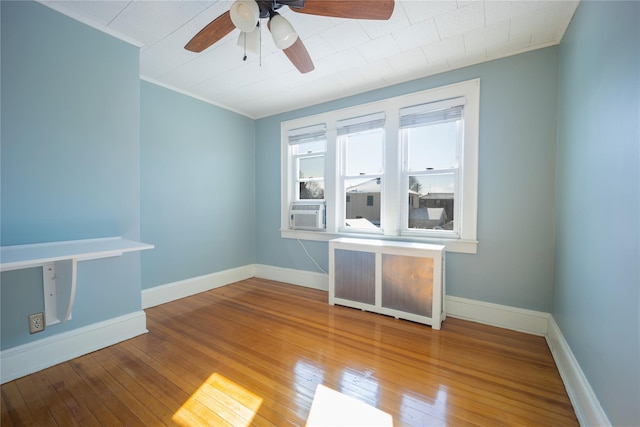 empty room with ceiling fan, hardwood / wood-style floors, radiator, and cooling unit