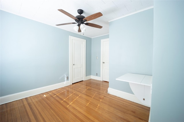 empty room featuring ceiling fan, hardwood / wood-style floors, and crown molding