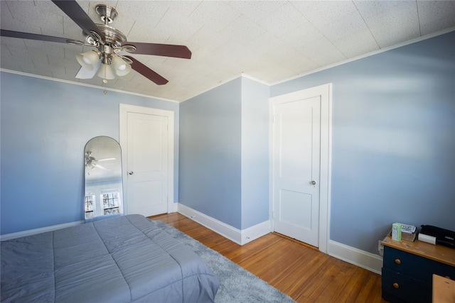 bedroom with ceiling fan, ornamental molding, and hardwood / wood-style flooring